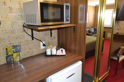 a kitchen with a microwave on a wooden counter at Tamworth Motor Inn & Cabins in Tamworth