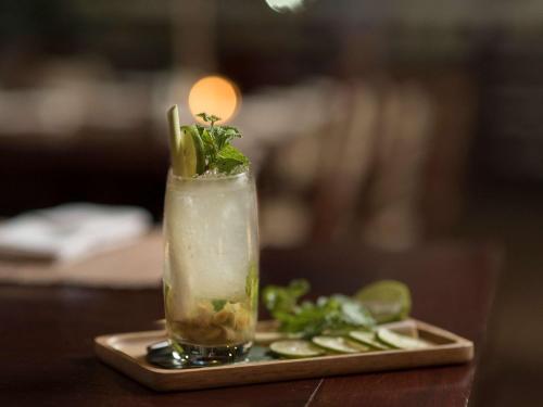 a drink sitting on a tray with cucumbers and greens at 3 Nagas Hotel Luang Prabang - MGallery Collection in Luang Prabang