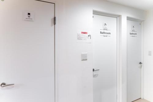 a row of white doors with signs on them at nestay inn tokyo senju in Tokyo