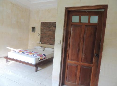 a bedroom with a bed and a wooden door at Lotus 2 Guest House in Borobudur