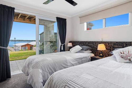 two beds in a bedroom with a large window at Omokoroa Sea View Apartment in Omokoroa