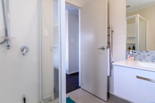 een witte badkamer met een wastafel en een spiegel bij Omokoroa Sea View Apartment in Omokoroa