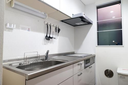 a kitchen with a stainless steel sink and a window at nestay inn tokyo senju in Tokyo