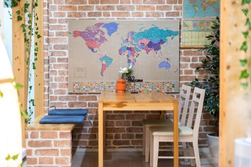 a table and chairs with a world map on the wall at nestay inn tokyo senju in Tokyo