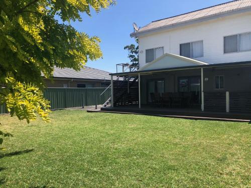 a house with a lawn in front of it at Callala Beach Shack - Pet Friendly in Callala Beach