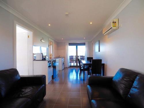 a living room with a black couch and a kitchen at Callala Beach Shack - Pet Friendly in Callala Beach