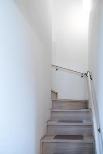 a staircase in a room with white walls and wooden steps at nestay inn tokyo senju in Tokyo