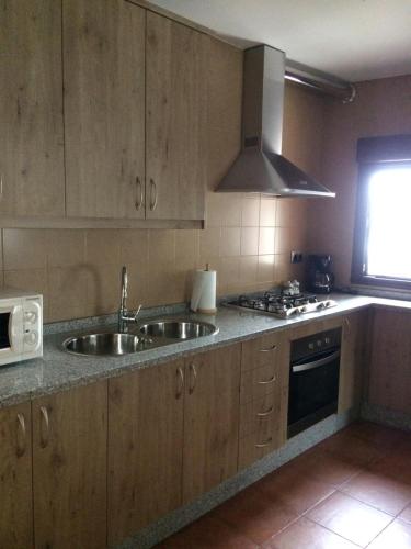 a kitchen with wooden cabinets and a sink and a microwave at Casa Rural El Pilón in Santibáñez el Alto