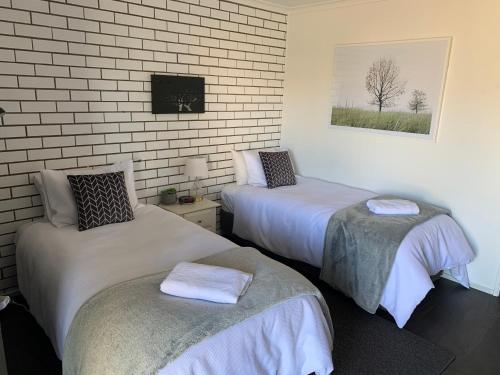 a bedroom with two beds and a brick wall at Kings Avenue Motel in Saint Arnaud