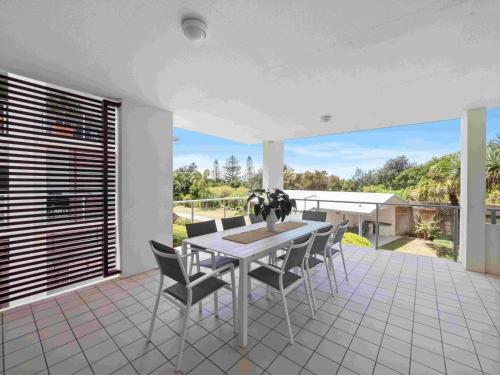 a dining room with a table and chairs on a patio at Pacific Marina Apartments in Coffs Harbour