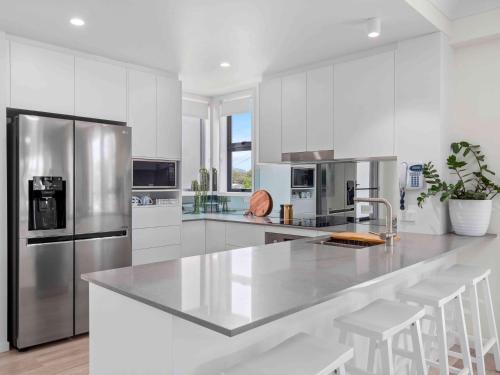 a kitchen with white cabinets and a stainless steel refrigerator at Pacific Marina Apartments in Coffs Harbour