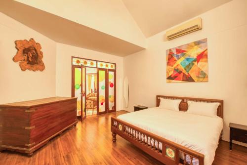 een slaapkamer met een bed en een schilderij aan de muur bij StayVista at Chitrita Bhavan with Indoor Game & Free Breakfast in Pondicherry