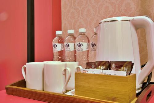 a tea kettle and cups and bottles of water on a shelf at Muen Yuan Dong Hot Spring Hotel in Jiaoxi