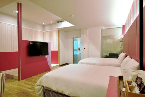a hotel room with two beds and a flat screen tv at Muen Yuan Dong Hot Spring Hotel in Jiaoxi