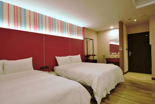 a room with two beds and a red wall at Muen Yuan Dong Hot Spring Hotel in Jiaoxi