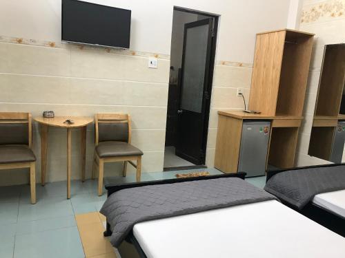 a room with two beds and a table and a tv at Thiên Các Hotel in Quy Nhon