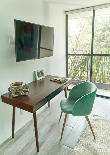 a desk and a green chair in a room with a window at Versátil departamento Ciudad de México in Mexico City