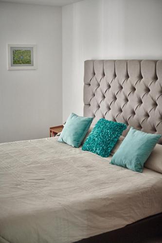 a large bed with two turquoise pillows on it at Versátil departamento Ciudad de México in Mexico City