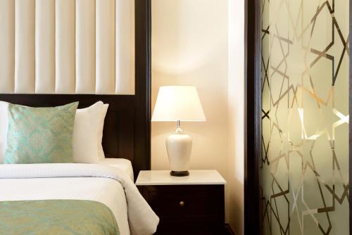 a bedroom with a bed and a lamp on a night stand at Ramada by Wyndham Lahore Gulberg II in Lahore