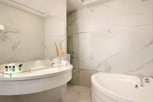 a white bathroom with a sink and a tub at Ramada by Wyndham Lahore Gulberg II in Lahore