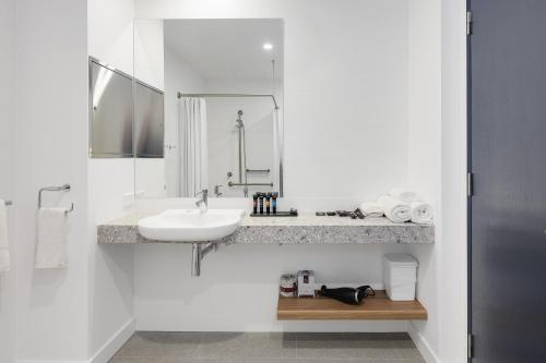 a white bathroom with a sink and a mirror at Springs Newcastle in Newcastle