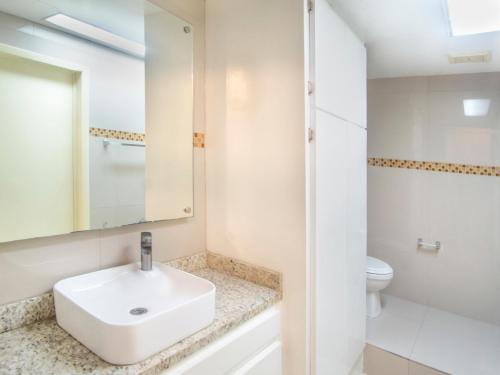 a white bathroom with a sink and a toilet at Hotel Regis in Mexicali
