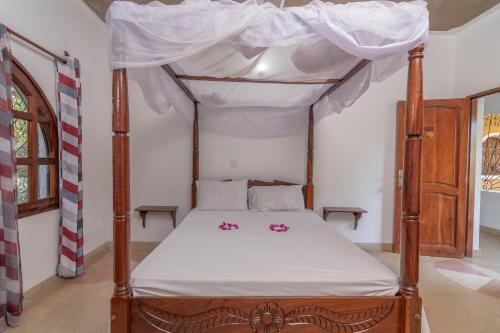 a bedroom with a canopy bed with pink flowers on it at JoysVilla Family Holiday Home in Malindi