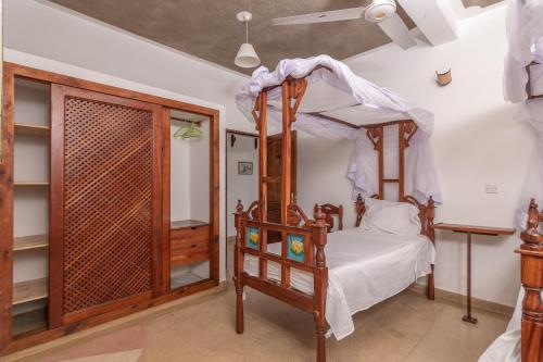 a bedroom with a canopy bed and a closet at JoysVilla Family Holiday Home in Malindi