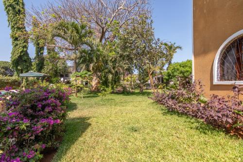 a yard with purple flowers and a building at JoysVilla Family Holiday Home in Malindi