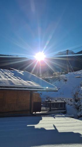 a snow covered roof of a house with the sun in the sky at Gasthof Wimbachklamm in Ramsau