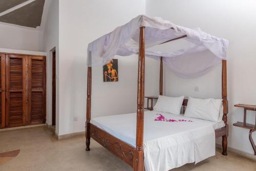 a bedroom with a canopy bed with white sheets at JoysVilla Family Holiday Home in Malindi