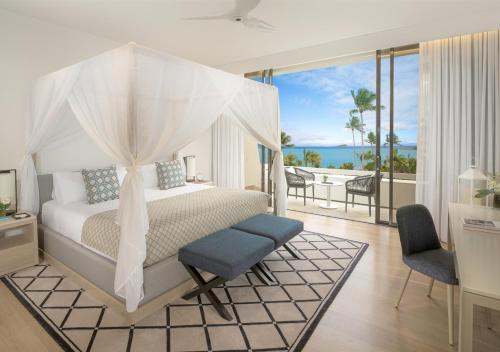 InterContinental Hayman Island Resort, an IHG Hotel في جزر هايمان: غرفة نوم مع سرير وشرفه مع المحيط