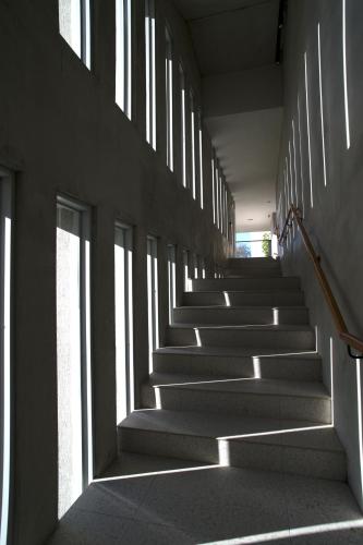 a staircase in a building with sunlight streaming through the windows at FFF Hotel in Hengchun