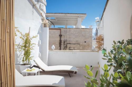 an outdoor patio with white chairs and plants at HolidayMonopoli in Monopoli