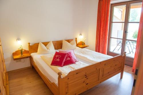 a bedroom with a wooden bed with two red pillows at Am Sonnenhang inkl. Chiemgaukarte in Ruhpolding