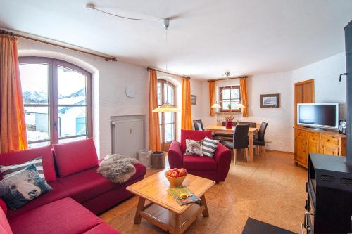 a living room with a red couch and a table at Am Sonnenhang inkl. Chiemgaukarte in Ruhpolding