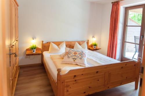 a bedroom with a wooden bed with pillows and a window at Am Sonnenhang inkl. Chiemgaukarte in Ruhpolding