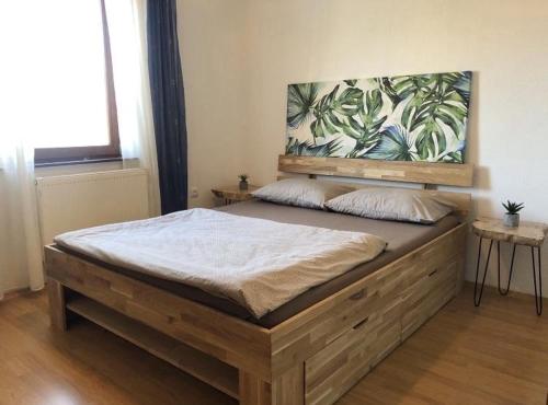 a bedroom with a wooden bed with a large painting on the wall at Apartman Nai in Bjelašnica