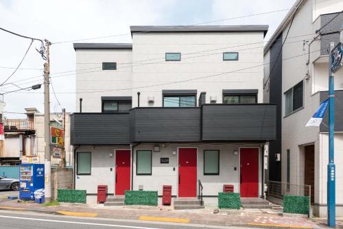 a building with red doors and a black roof at Terrace house omori in Tokyo