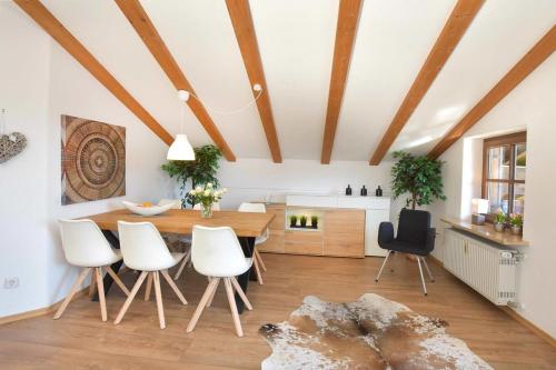 a dining room with a wooden table and white chairs at Am Sonnenhang inkl. Chiemgaukarte in Ruhpolding