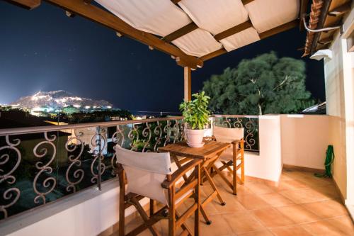 a balcony with a table and chairs at night at Afrodite Hotel Apartments in Mirina