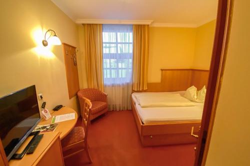 a small hotel room with a bed and a desk at Landhotel Gasthof Bauböck in Andorf
