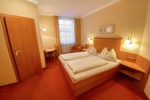 a hotel room with a bed and a desk at Landhotel Gasthof Bauböck in Andorf