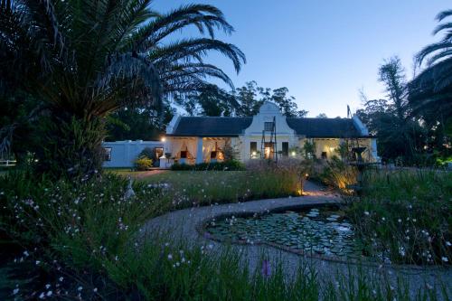 a house with a pond in front of it at Lairds Lodge Country Estate in Plettenberg Bay