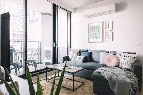 ein Wohnzimmer mit einem blauen Sofa und einem Tisch in der Unterkunft 2 BR Modern Melbourne CBD Apartment in Melbourne