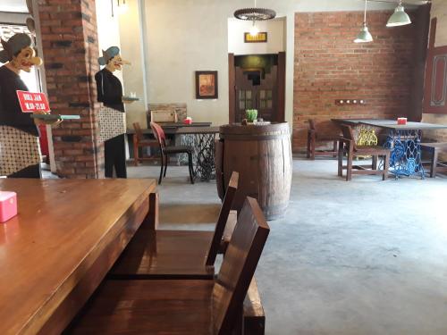 two women standing in a room with tables and chairs at Griya Gribig Guest House Mitra RedDoorz in Malang