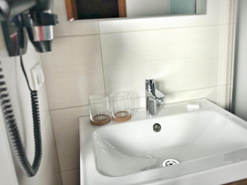 a bathroom sink with two glasses and a phone at Gasthof Auwirt in Sankt Michael im Lungau