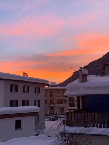 a sunset over the roofs of buildings with snow at Hotel Spöl Restaurant in Zernez