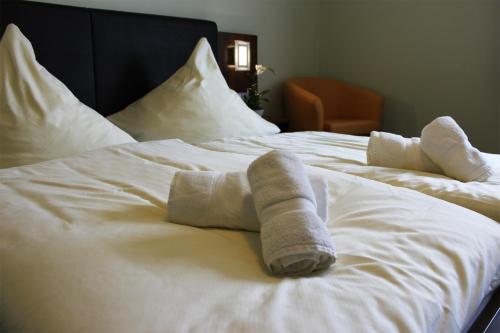 un letto bianco con due asciugamani arrotolati di Hotel Brantl a Roding