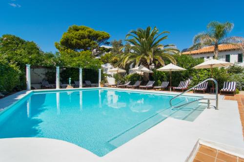 uma piscina com cadeiras e guarda-sóis em The Sea Club em Cala Ratjada